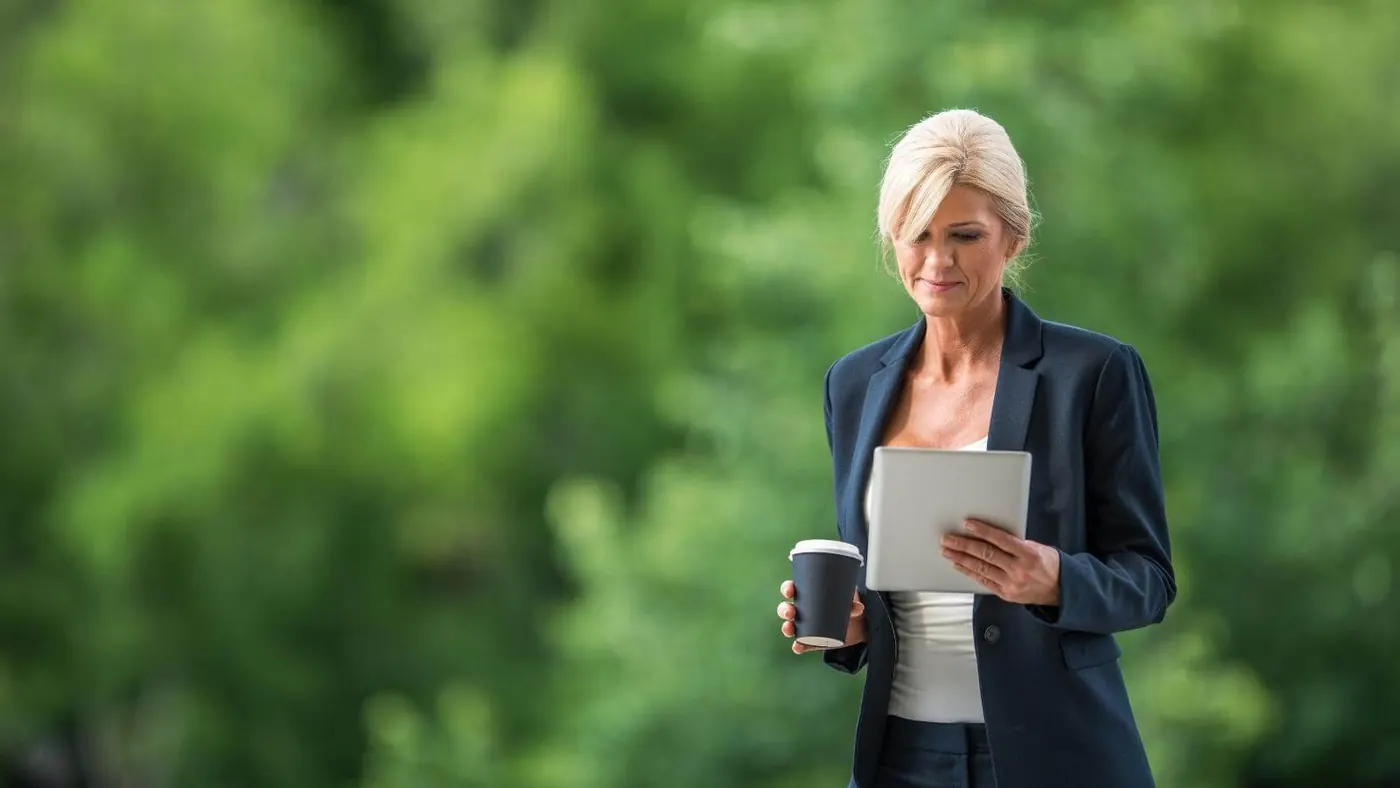 Woman drinking coffee looking at tablet