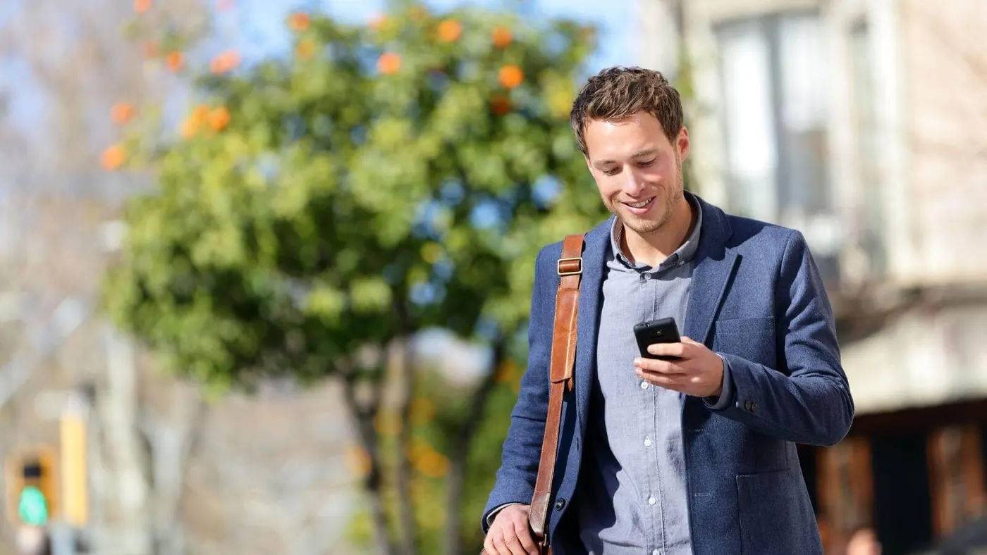 Man checking his phone while walking outside