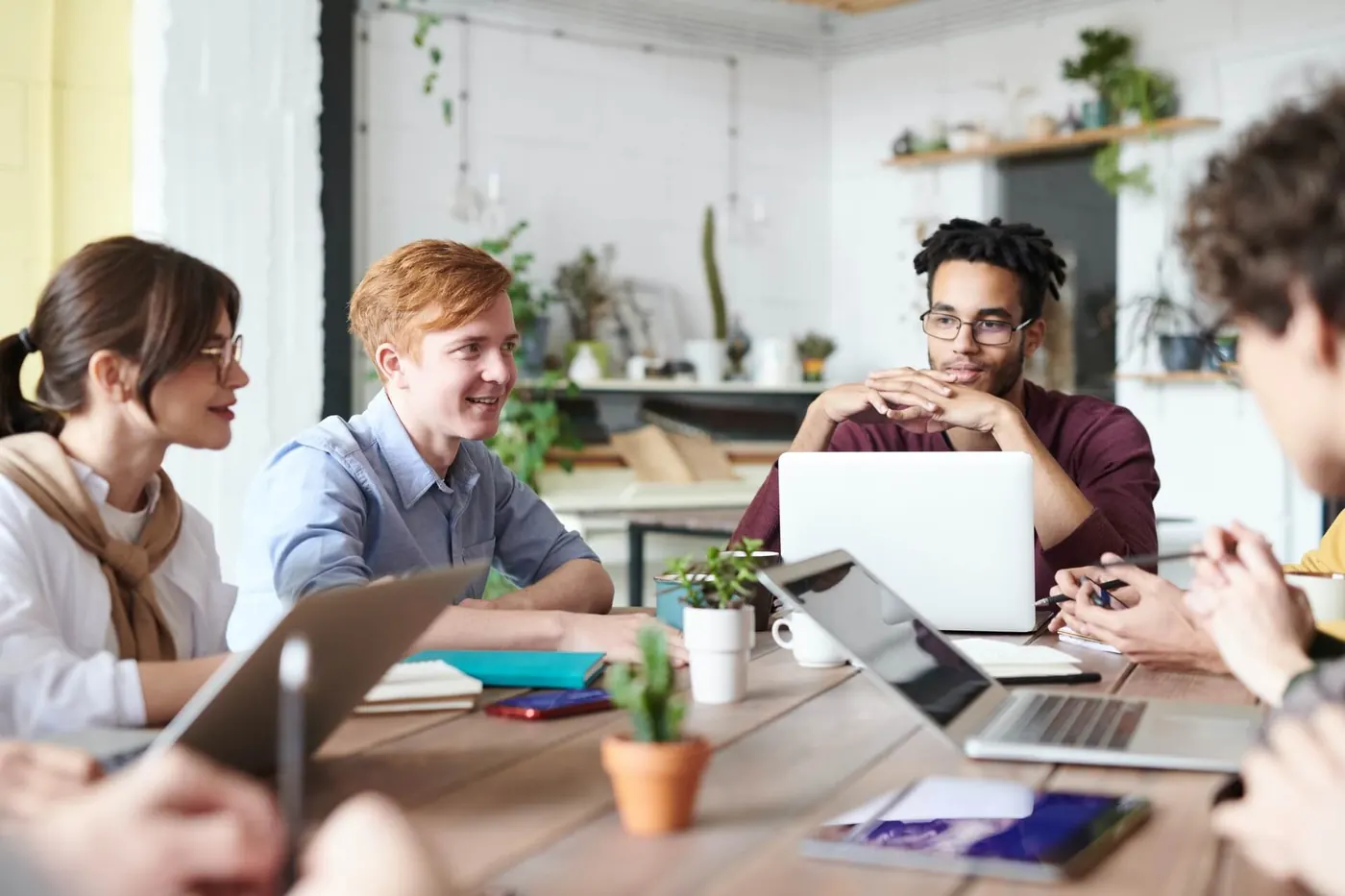 Image of smiling marketers sitting at a table together with laptops, building engagement strategy