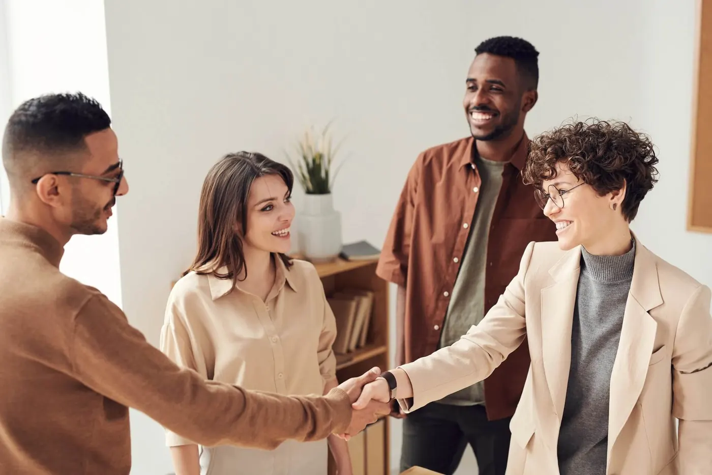 Group of marketeters smiling as two shake hands