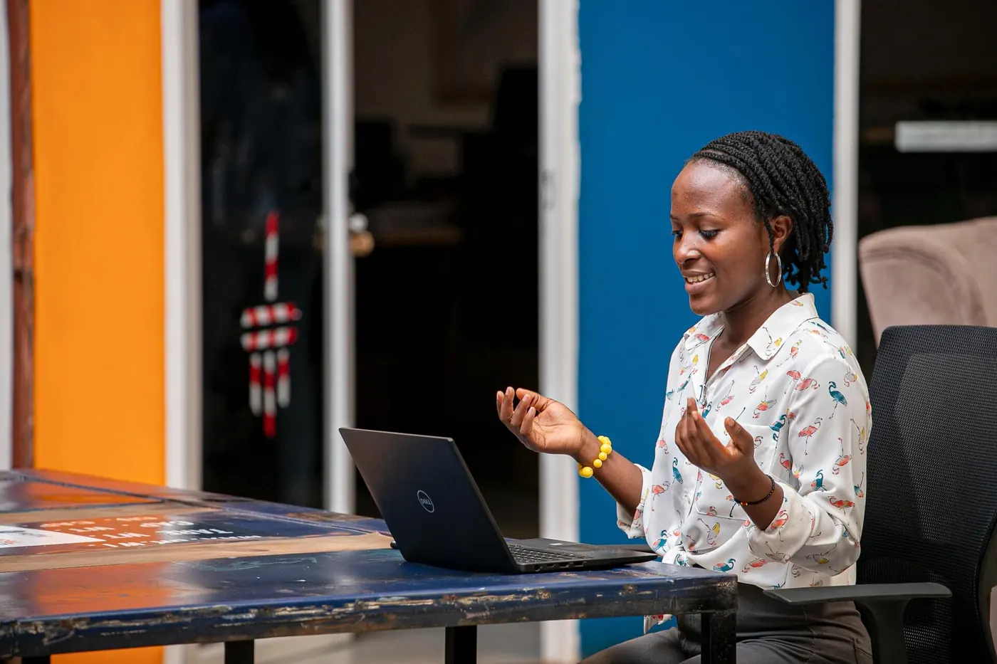 Marketing woman sits at computer and smiles, gestures, to her webinar attendees